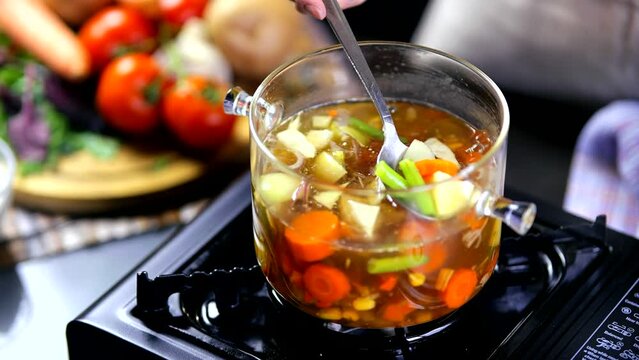 woman stirring pot of vegetable soup