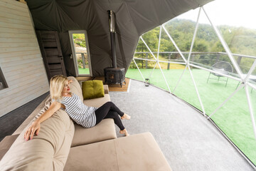 a woman is soldering in the transparent dome of the glamping hotel