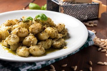 Piatto di deliziosi gnocchi di patate conditi con pesto alla genovese, cibo italiano 