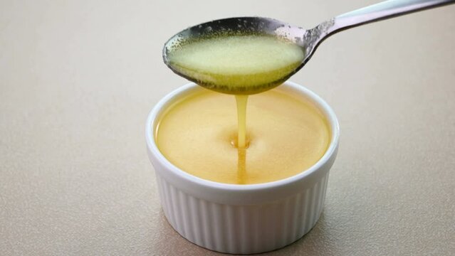 Pouring ghee in a bowl using a spoon.