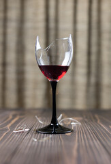 A broken wine glass on a wooden table. Selective focus.