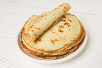 Pancakes on a white plate. A lot of pancakes are stacked. Thin pancakes with a crispy crust. Pancake day. Pancakes for breakfast and carnival.
