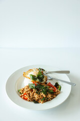 Pad Kra Pow with chicken in bowl with rice and fried thai basil