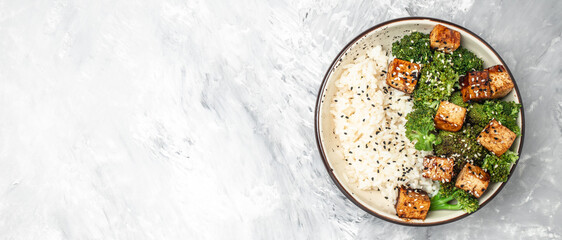 Savory sauteed mixed chinese rice, broccoli with fried tofu, Asian vegan bowl, Long banner format. top view