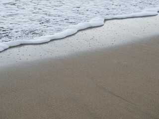 Fototapeta na wymiar Gentle ocean blue wave on a clean sandy beach