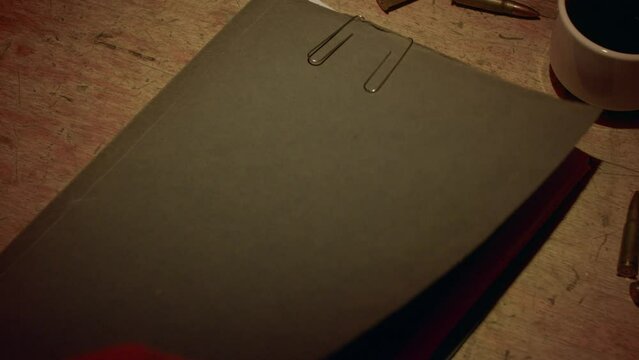 A retro manilla folder containing documents marked 'Top Secret' is seen on a wooden table lit by subdued light.