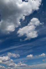 Blue sky with clouds. Spring or summer background. 
White clouds on the blue sky have a complex pattern.

