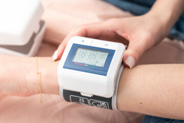 Close-up of wrist blood pressure monitor on female hand measuring pulse and blood pressure. Health care and check up concept