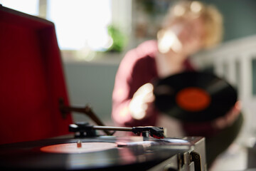 Teenage Girl Playing Vinyl Records On Record Player At Home In Bedroom With Focus On Foreground