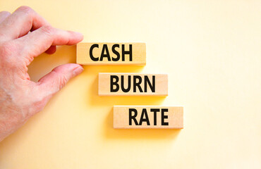 Cash burn rate symbol. Concept words Cash burn rate on wooden blocks on a beautiful white table white background. Businessman hand. Business cash burn rate concept. Copy space.
