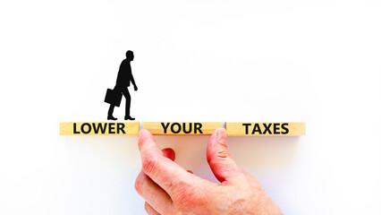 Lower your taxes symbol. Concept words Lower your taxes on wooden blocks on a beautiful white table white background. Businessman hand. Business tax lower your taxes concept. Copy space.