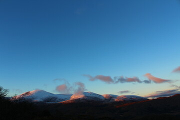 Setting sun hitting the top of snow covered Irish mountains in winter - Lady's View, Killarney National Park, County Kerry, Ireland