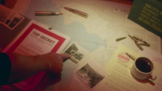 A retro manilla folder containing documents marked 'Top Secret' is seen on a wooden table lit by subdued light.