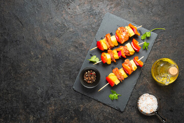 Raw prepared skewers with chicken, pineapple and sweet peppers on a black slate board against a black concrete background. Step by step recipes, cooking.