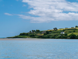 Beautiful sky over a water on a summer day. The picturesque green coast of Ireland. Several...