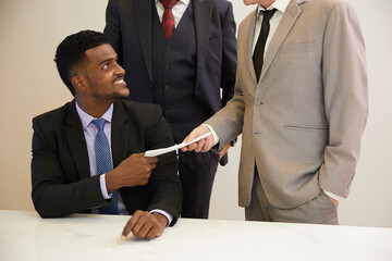 African businessman giving envelope to his boss in the office