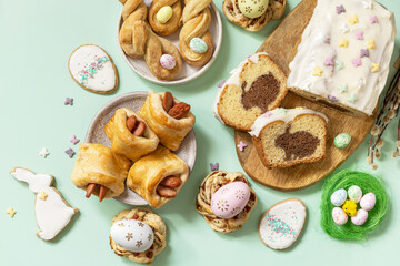Festive dinner, Easter brunch. Happy Easter holiday food baking puff pastry and cupcake with Easter Bunny on pastel green background. View from above.