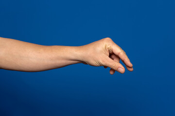 Man hand stretches out to take, arm body part of people isolated on blue background