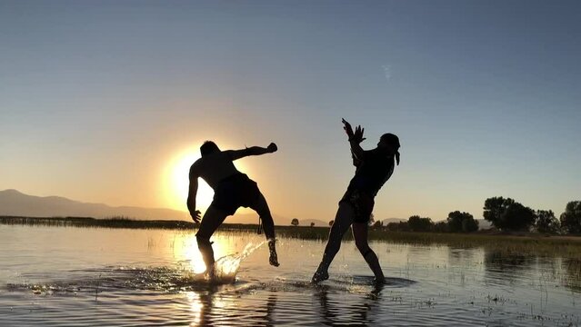 duo practicing muay thai fight in lake waters at sunset