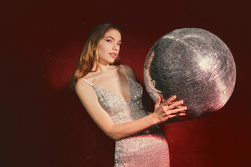 Naklejka premium an elegant woman in a shiny festive dress poses with a shiny ball