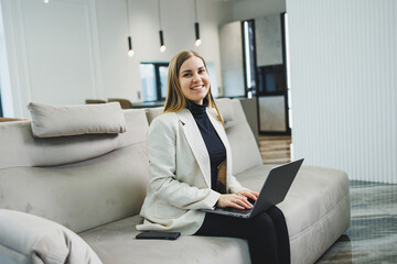 Woman cheerful charming person sitting behind a netbook watching having a good mood working at home indoors. Remote freelance work