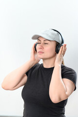 Portrait of a girl on a white background with wireless headphones and a hat on her head.
