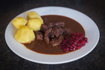 ready to eat, delicious goulash of chamois meat in a brown sauce with potatoes and cranberries