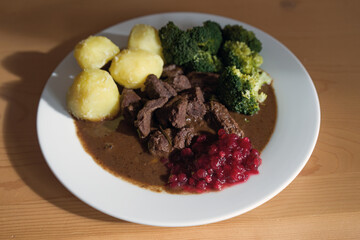 ready to eat, delicious goulash of chamois meat in a brown sauce with potatoes and cranberries