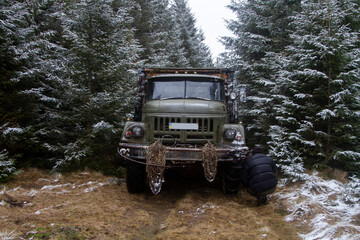 An old military truck in a green swamp with metal chains in the forest, Carpathians