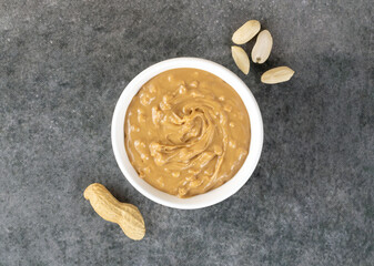 Crispy peanut butter in a bowl and peanuts on a gray background. Top view. American food.