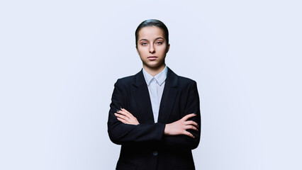 Obraz na płótnie Canvas Serious teenage female student in black suit looking at camera on white background