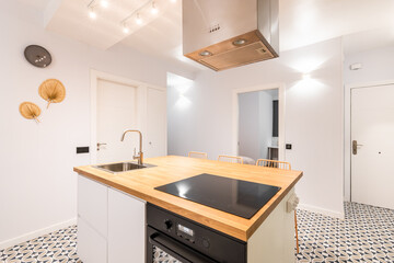 Wooden table and high chairs at the center of bright warm kitchen of modern apartment with appliances