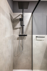 Closeup of the shower area. Moisture resistant gray marble tile walls. On the wall is a black...