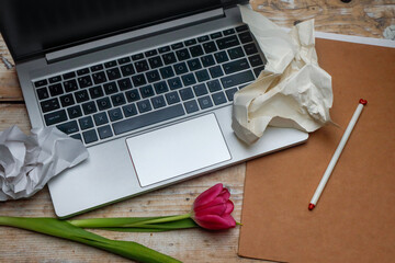 Workplace - laptop, headphones, paper and pen - a creative mess with flowers
