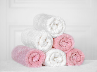 White and pink towels are twisted on a light background