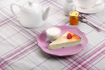 A piece of cottage cheese casserole on a pink plate. Breakfast.
