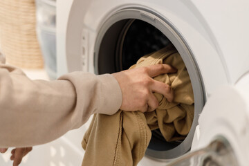 Man's hands putting clothes in the washing machine