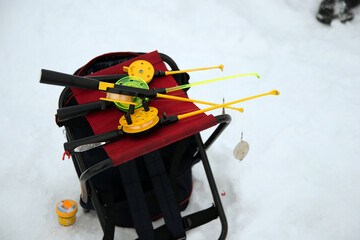 Unrecognizable person holding a plastic ice fishing rod on an iced lake.