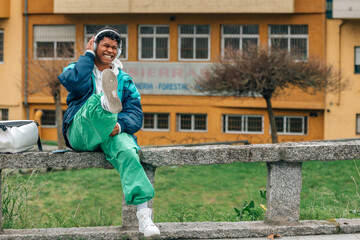 young latin man listening to music on the street with headphones