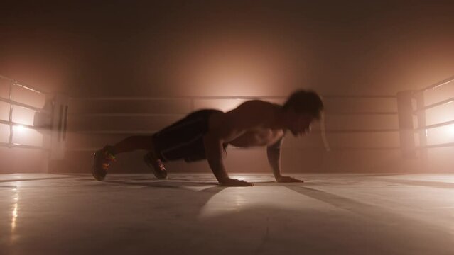 Close-up shot of professional boxer pushing up and clapping behind his back. Portrait of a male athlete boosting his stamina and endurance while preparing for a sparring. High quality 4k footage