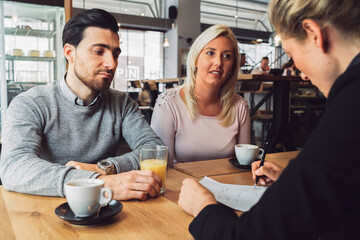 Young couple on a meeting having some coffee with their real estate agent 