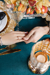 The hands of lovers hold each other on the background of a table decorated for an engagement. She said yes.