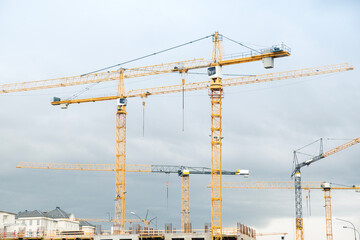 Fototapeta na wymiar Construction site with yellow cranes on a cloudy day. Development area