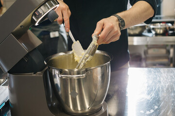 Making macarons. A silver kitchen table mixer kneads the dough for macarons.