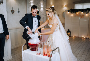 A young, stylish groom in a black suit and a beautiful blonde bride with a diadem in a dress...