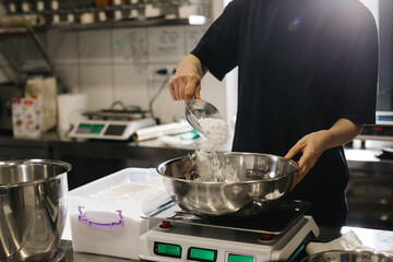 A woman cook works in a modern industrial kitchen. The process of making cakes in a bakery or cafe.