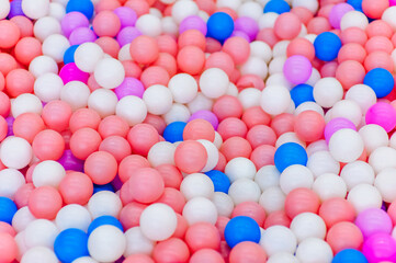 Background, close-up texture of many colored, multi-colored round plastic small balls on the playground for children's games. Photography, top view, copy space, childhood concept.