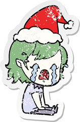 distressed sticker cartoon of a crying vampire girl wearing santa hat