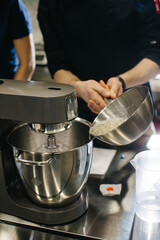 The chef works with a dough mixer. Adding caramel, close-up.