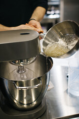 The chef works with a dough mixer. Adding caramel, close-up.